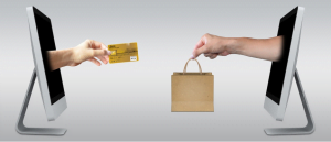 Two computer screens with hands coming out of them exchanging purchases for credit card information.