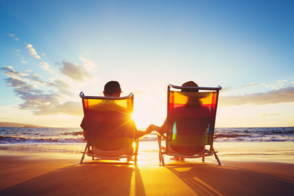 Older couple sitting on the beach enjoying the sunset