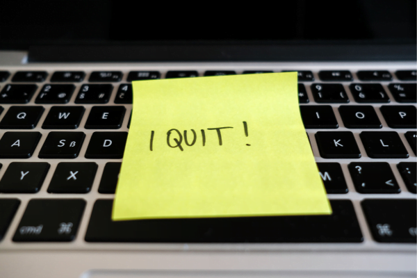 Post it note with "i quit" written on it left on a keyboard.