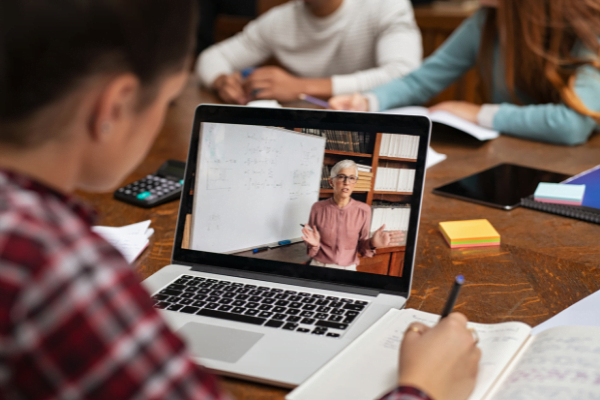 Man sitting in front of a laptop watching an online course.