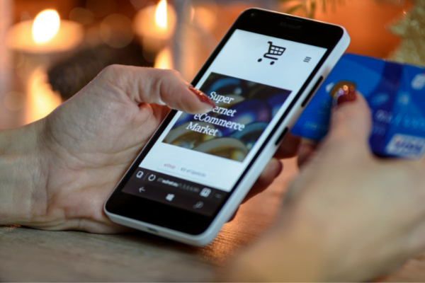 Woman's hand holding a credit card and doing online shopping with her phone.