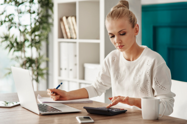 Woman using her computer and a calculator to look over her finances