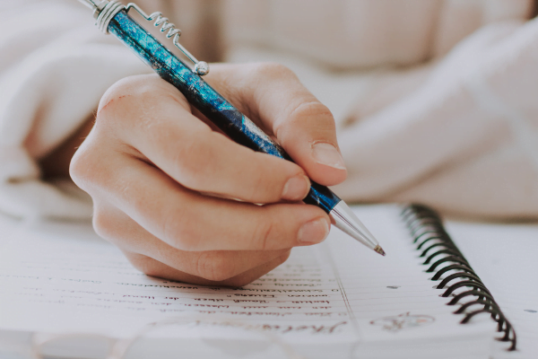 hand with a pen writing details into a planner