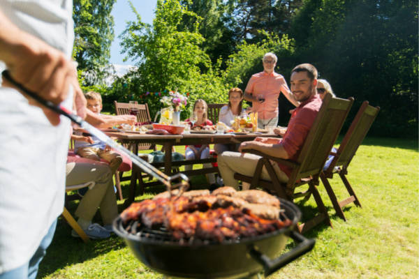 family and friends watching someone cook on a bbq